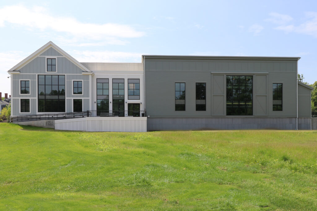 Back exterior of the Arts Center featuring a deck for gathering and green lawn in the foreground