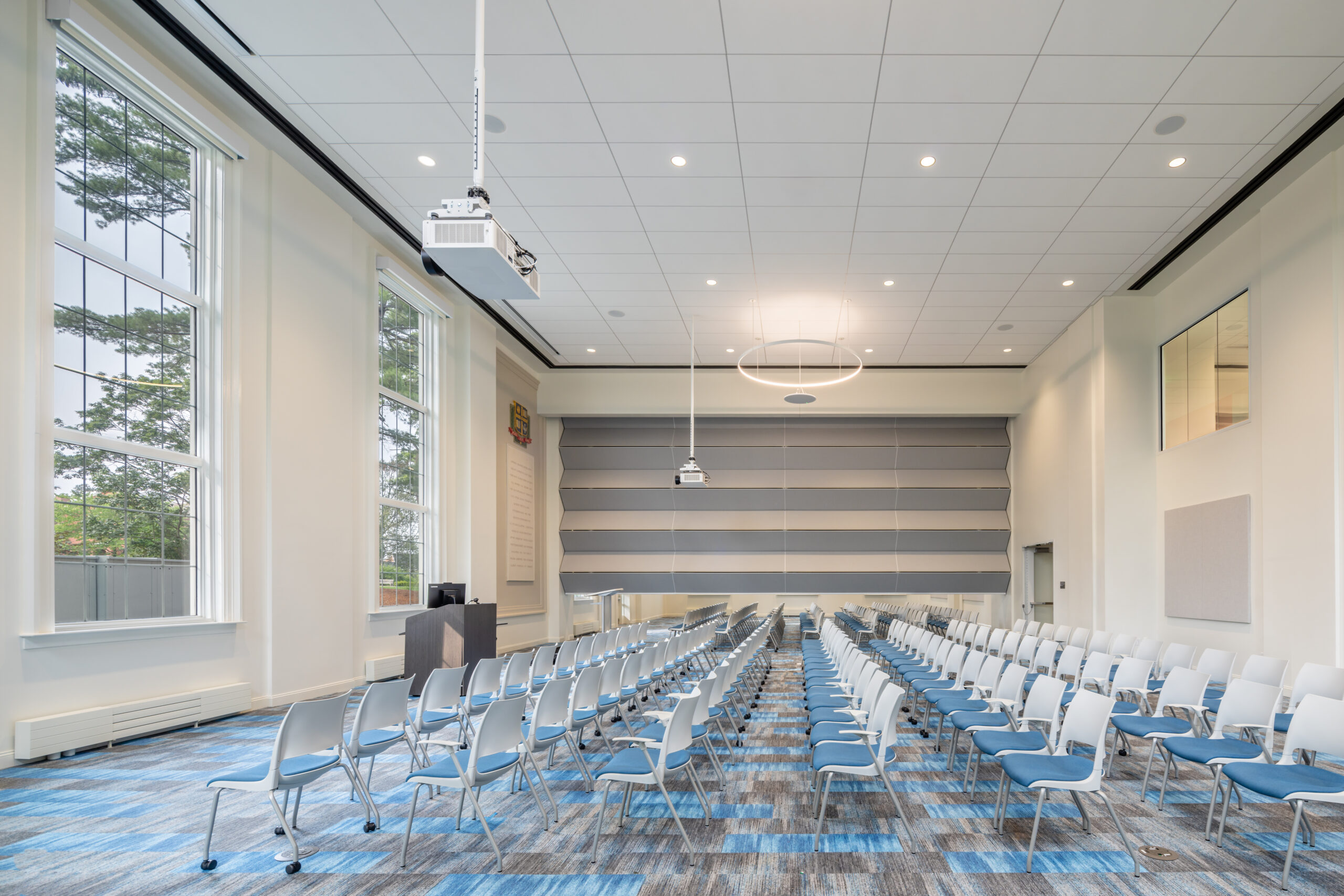 Tufts-EatonHall-Final-HiRes-6 Auditorium with chairs and podium set up for an assembly, with the divider splitting the room into two