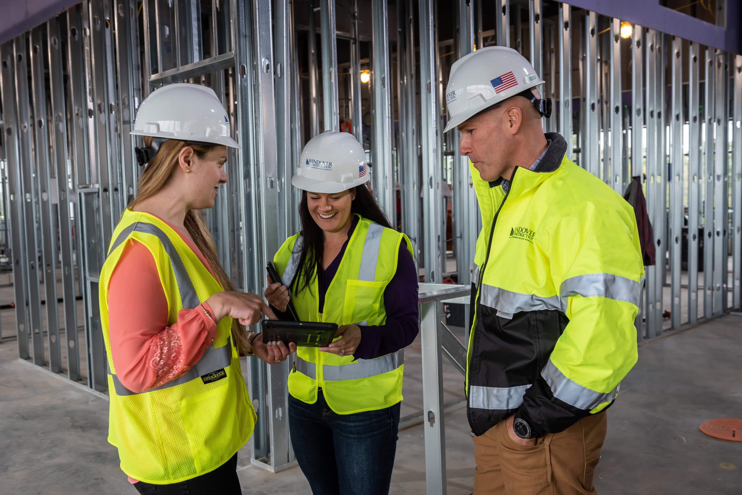 Three employees in hard hats and vests at construction site