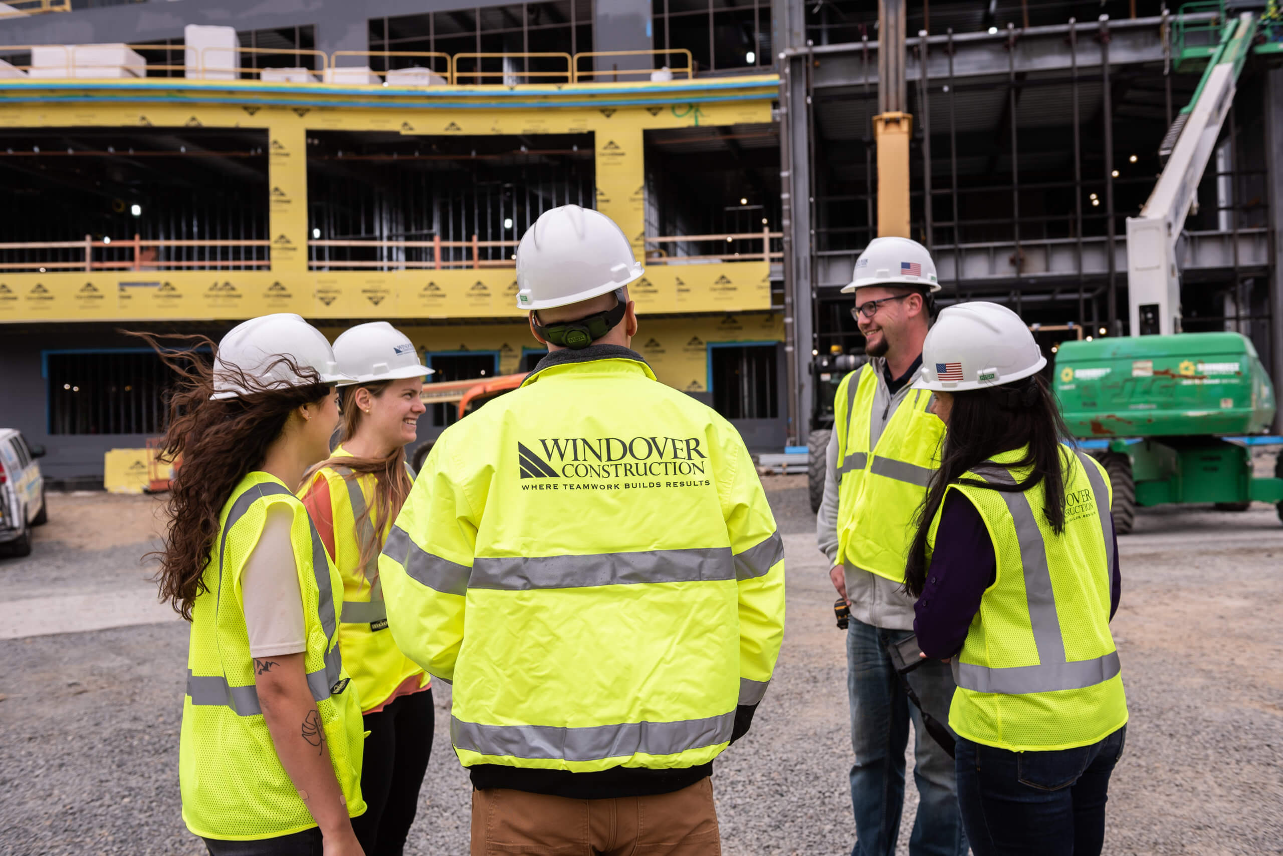 Construction site with people in a circle wearing Windover hard hats and vests